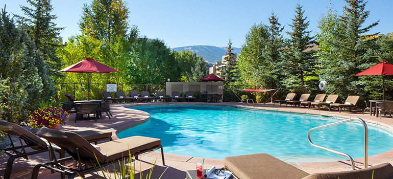 Pool area at a Colorado resort surrounded by pine trees with mountains in the background