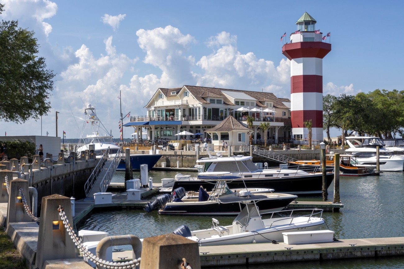4.	A series of boats sits in a harbor with a lighthouse and restaurant just off the shore.