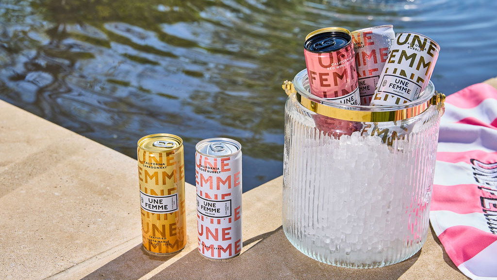 2)	A cooler with cans of Une Femme sparkling wine on a striped towel.