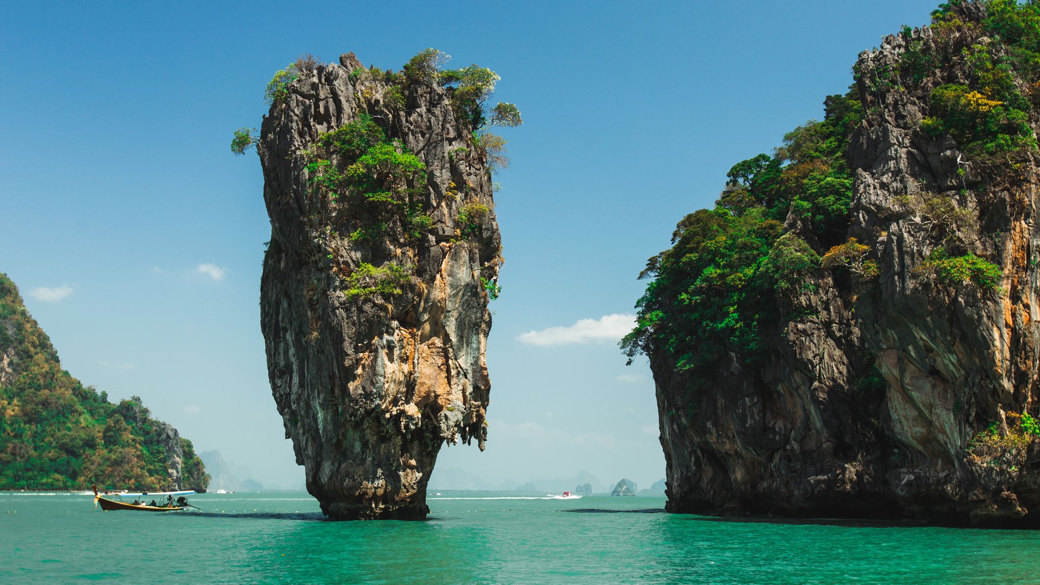 Two mini mountains sit in the middle of the water on a beach in Thailand.