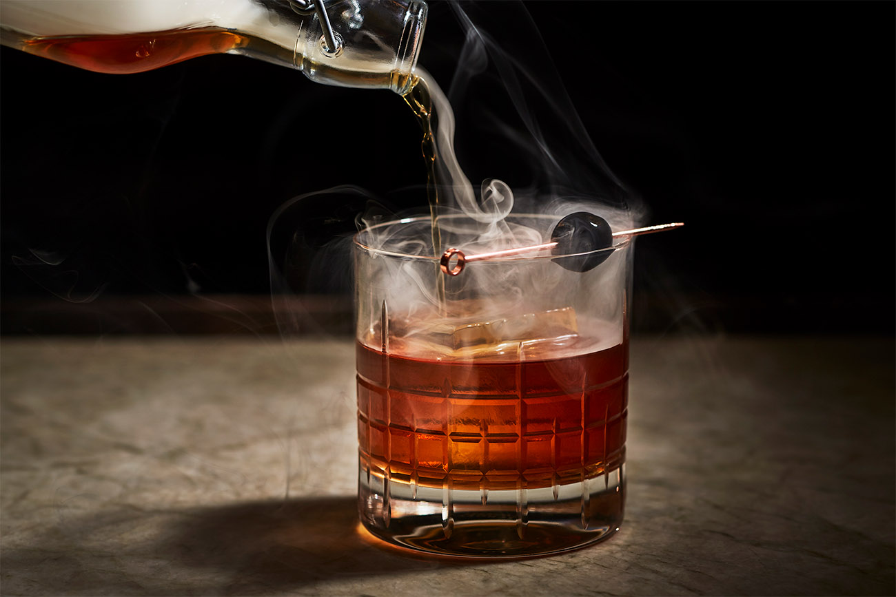 Bourbon is being poured into a glass filled with ice.