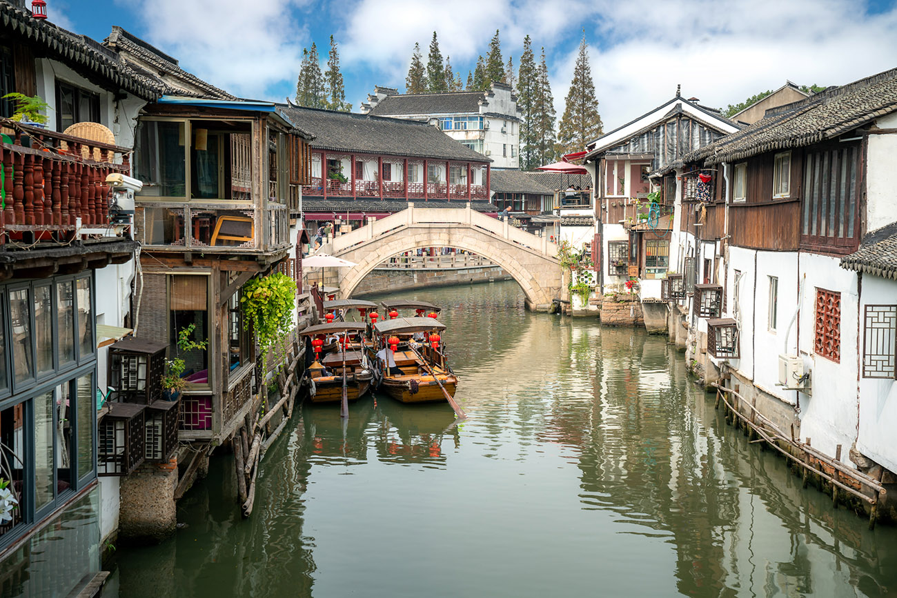 Shanghai Water Town with a narrow canal, arched stone bridge, and traditional buildings.