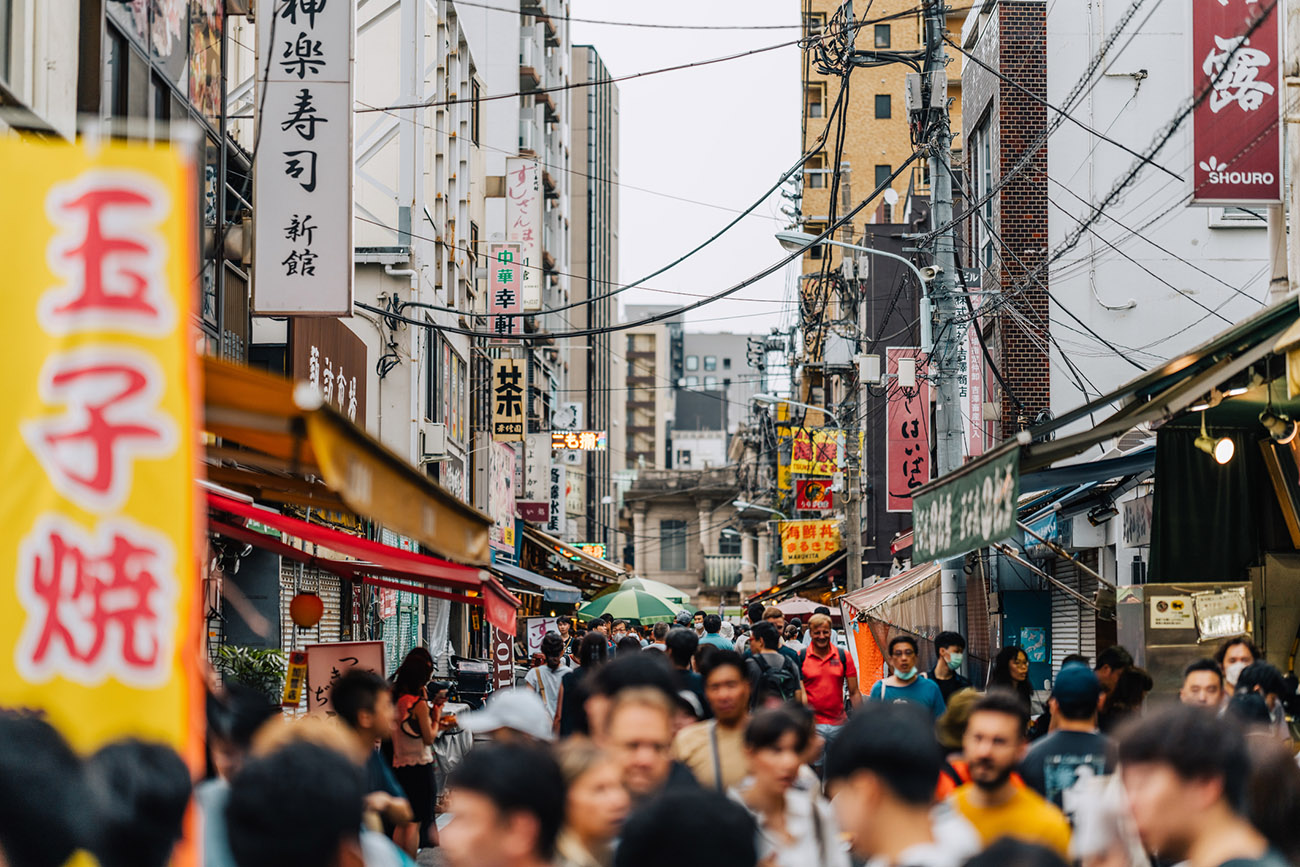 Crowded Tokyo street lined with tall buildings and bright Japanese signage.