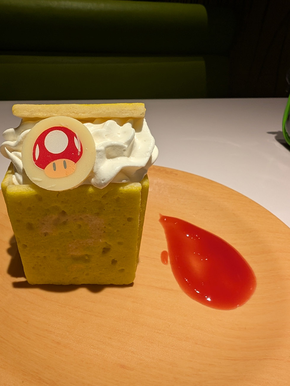 Dessert shaped like Mario’s face on a plate, with a spoon and napkin beside it.