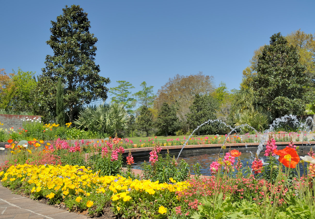 Landscaped garden at Brookgreen Gardens featuring a pond, flowering plants, and classical sculptures.