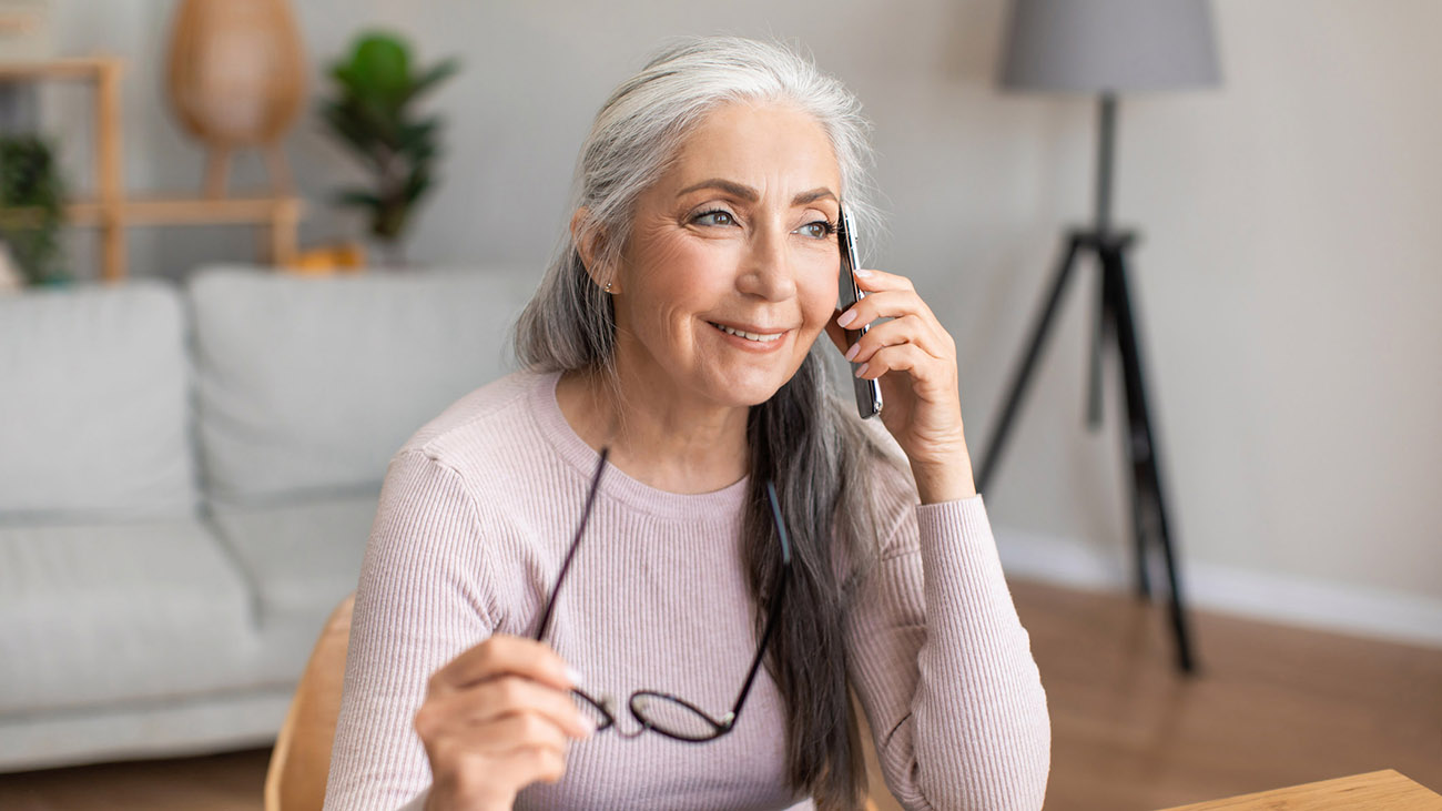 A woman sitting at a desk talks on the telephone.