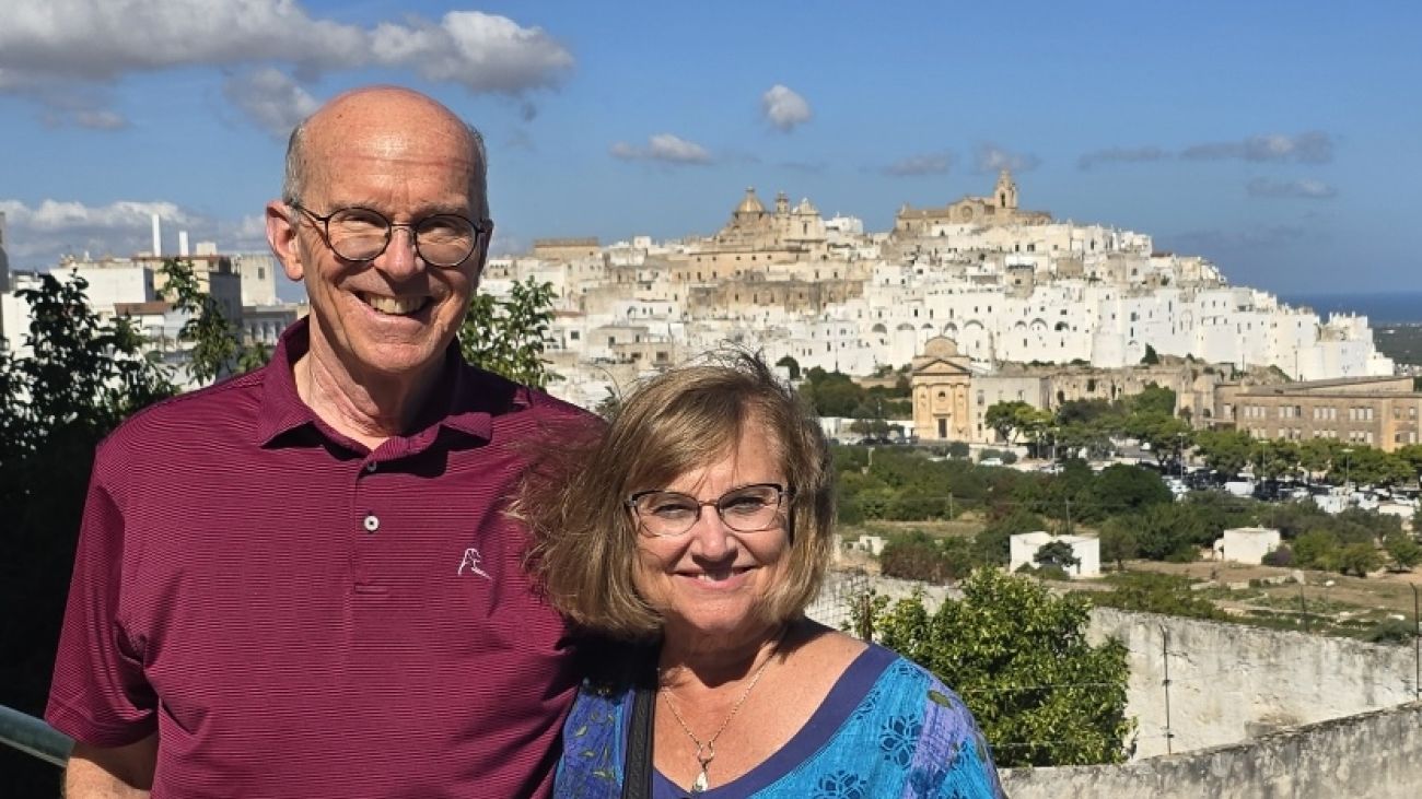 Newlyweds Andy Boye and Lori Kruczek pose smiling in front of historic stone buildings.