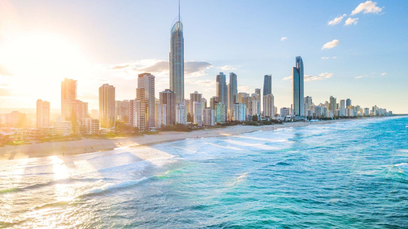 The Surfers Paradise skyline shines as the sun rises behind the skyscrapers.