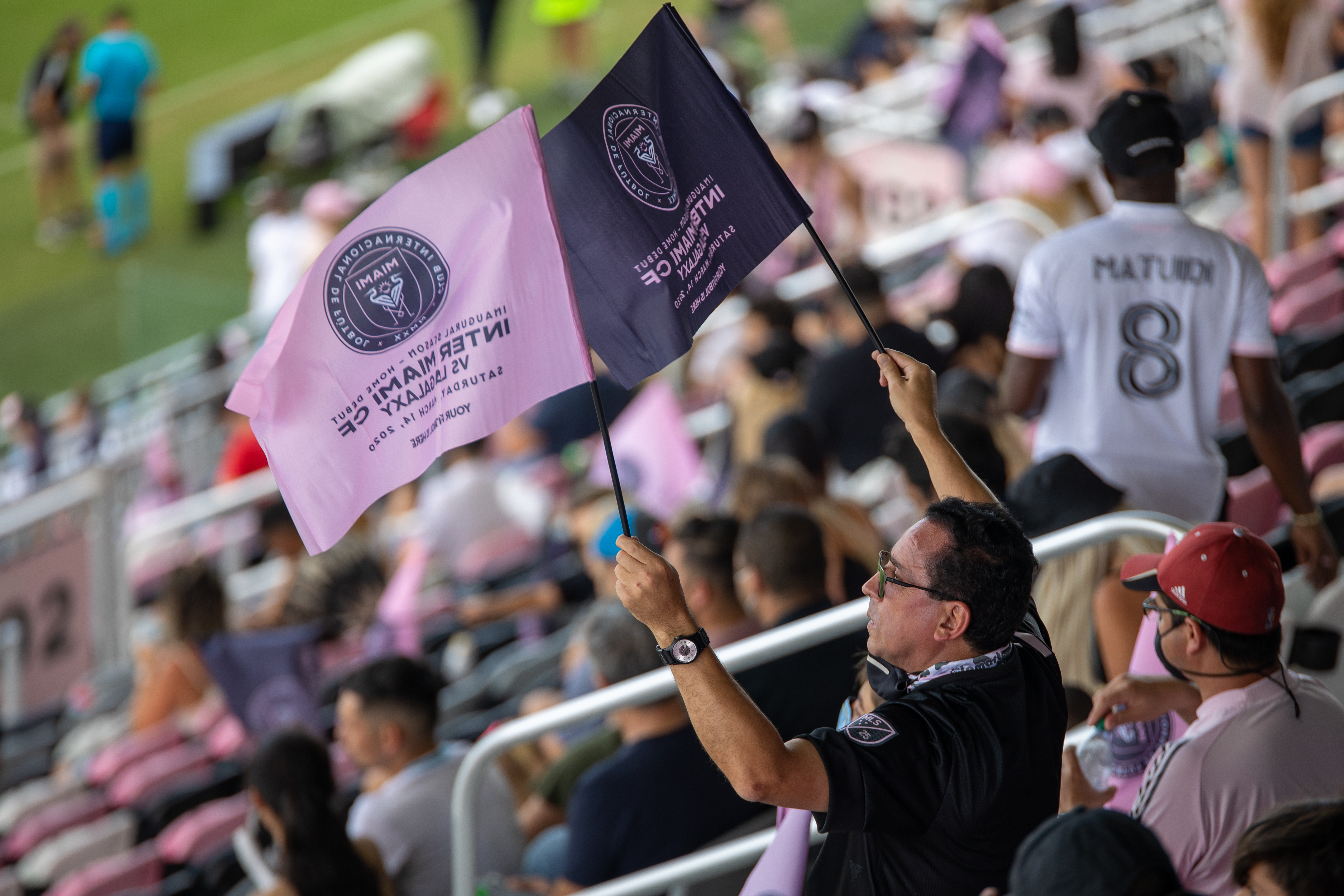 A soccer fan holds up team flags during a game.