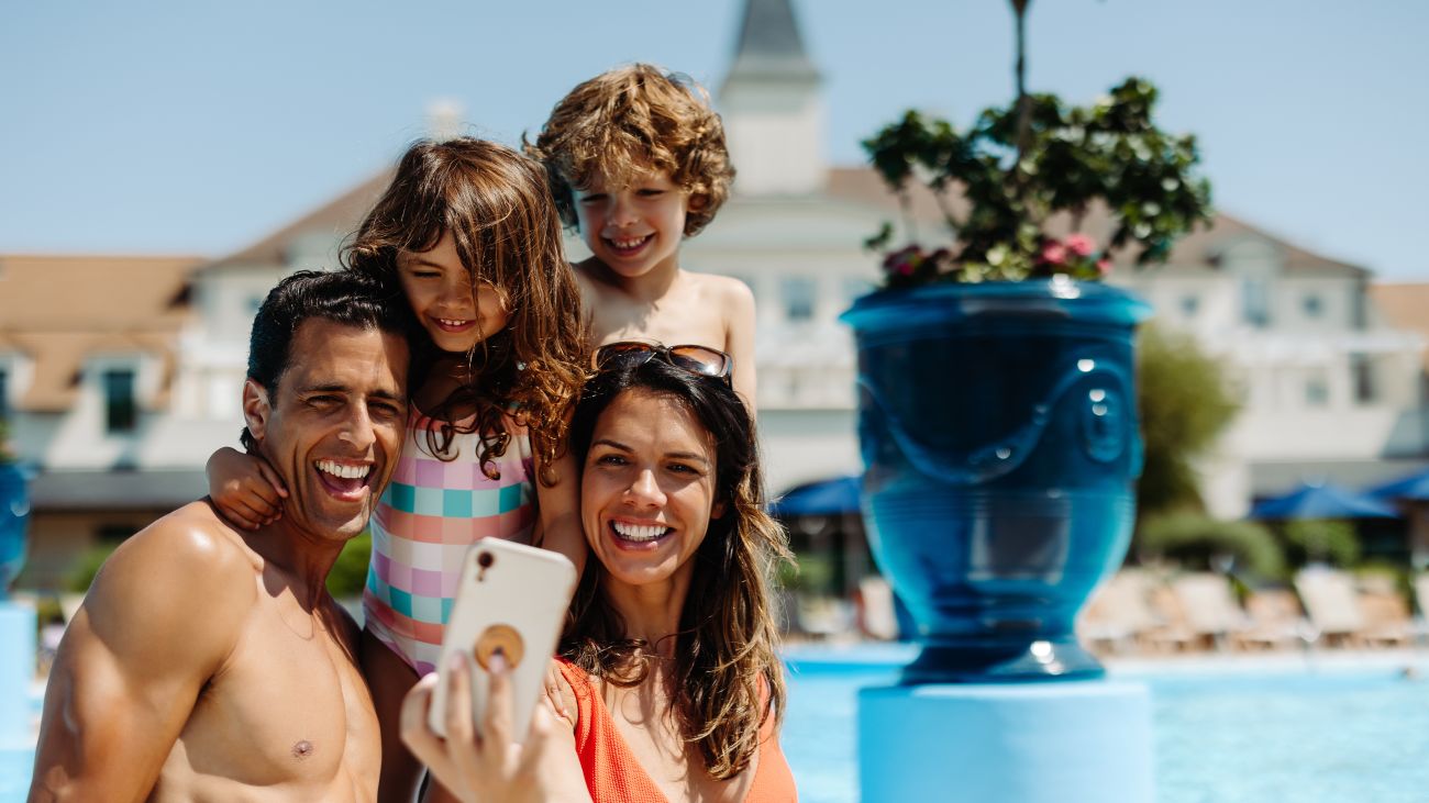 A group of friends huddle together to take a selfie while swimming in the resort pool.