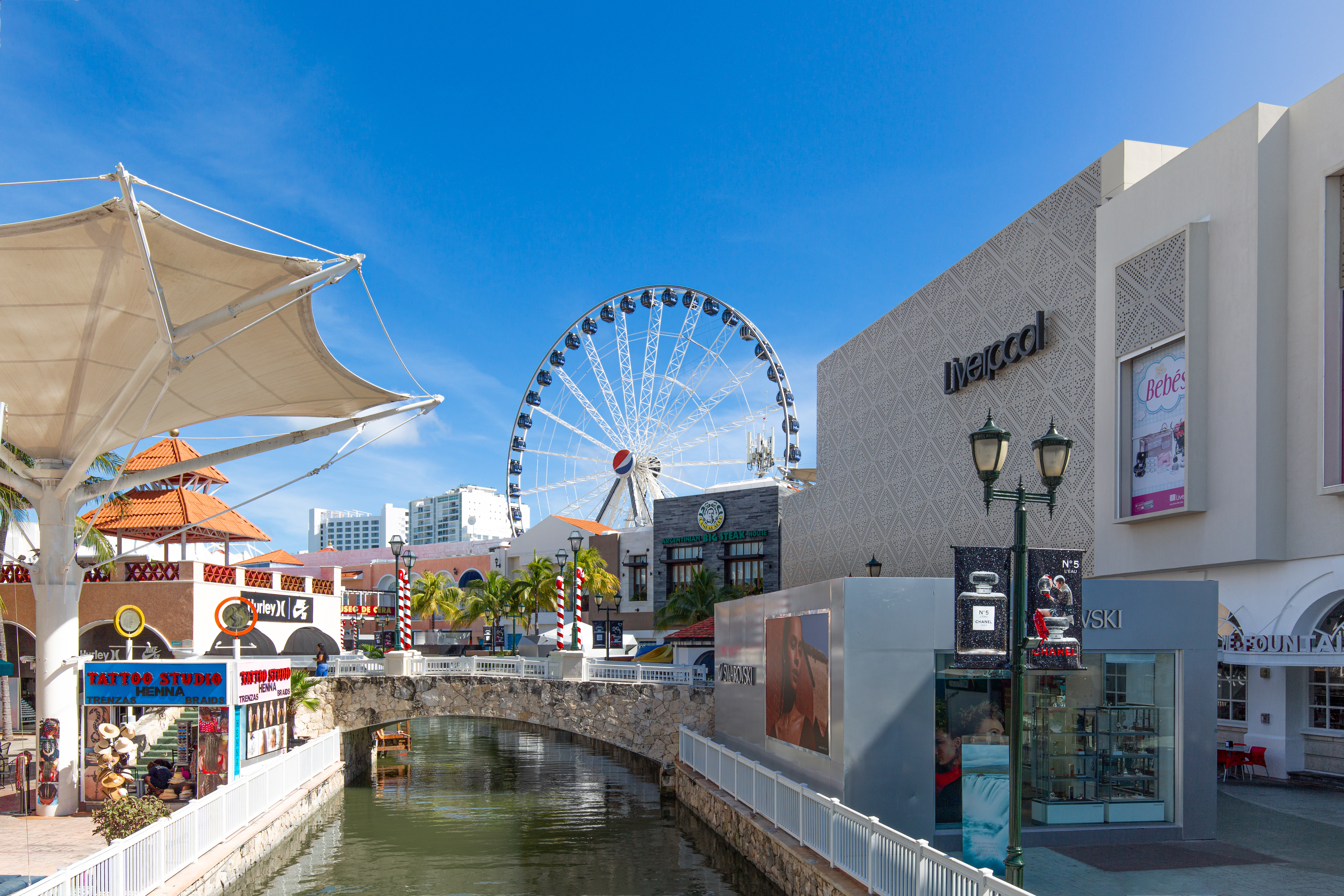 A large Ferris wheel sits behind a shopping center.