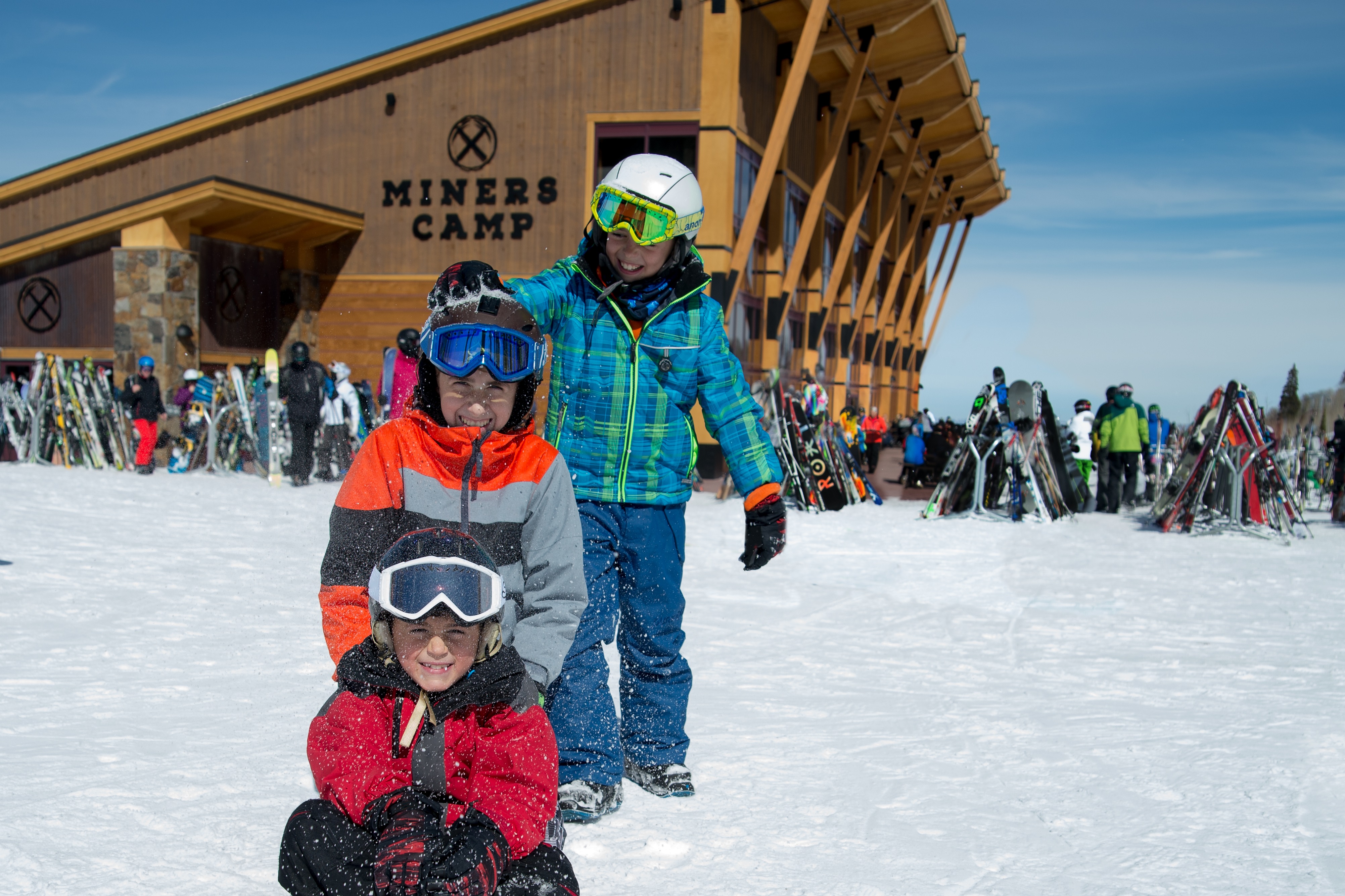  Three young children in ski gear play in the snow.   