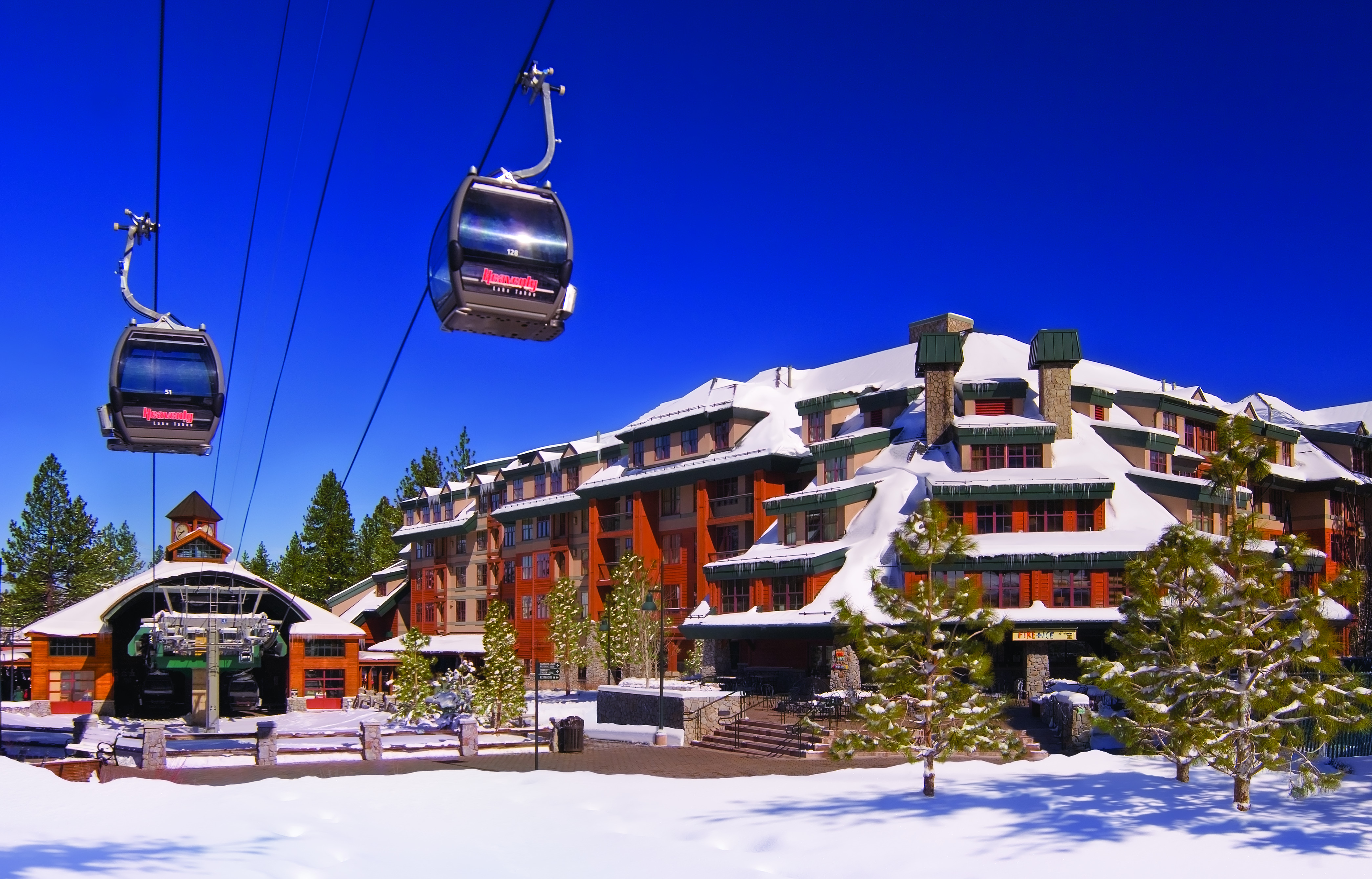 A gondola in front of a snow-covered resort.