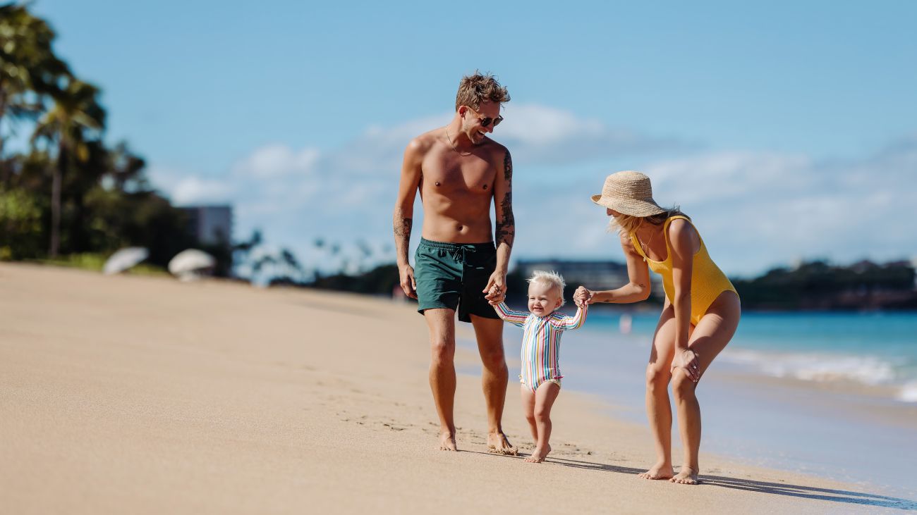 A family walks along a sandy beach near the ocean. 