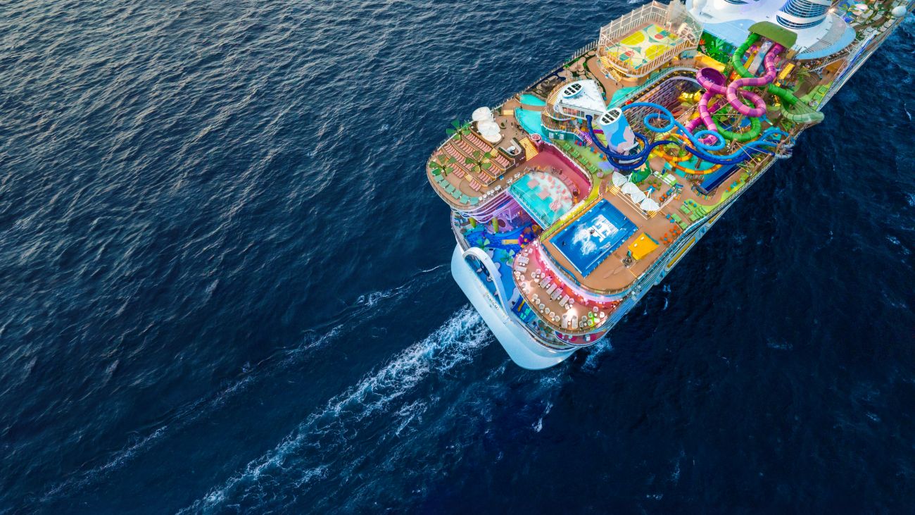 An aerial view of a vibrant cruise ship sailing through deep blue water. 