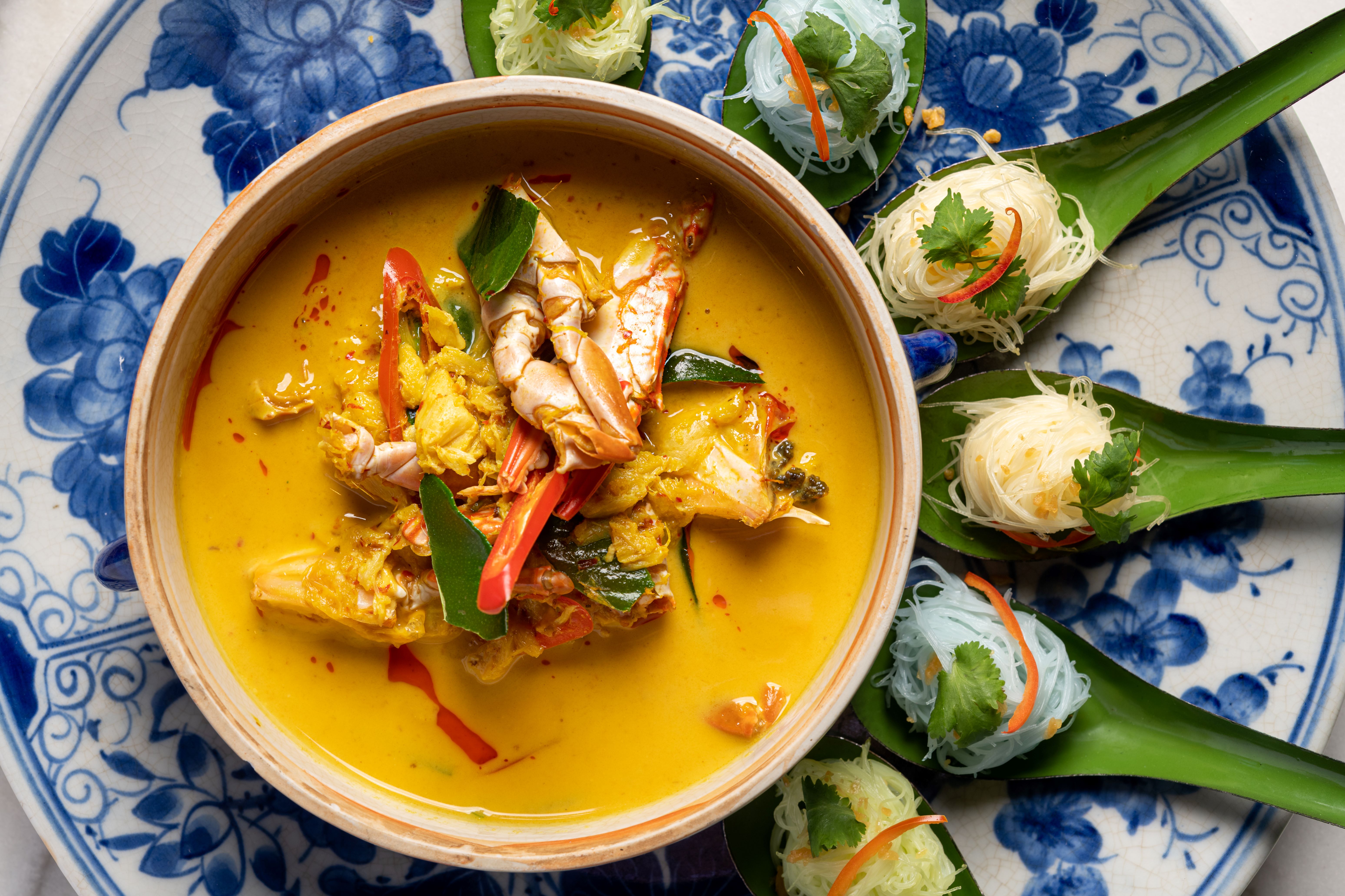 A bowl of yellow Thai curry served on a patterned blue-and-white plate.